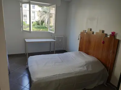 a bedroom with a bed and a table and a window at 3 pièces 67m2 centre ville très lumineux et calme in Nice