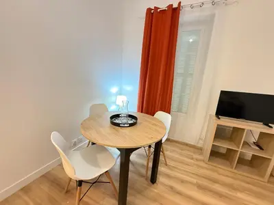 a dining room with a table and chairs and a television at Villa Amira Angely Vauban in Nice