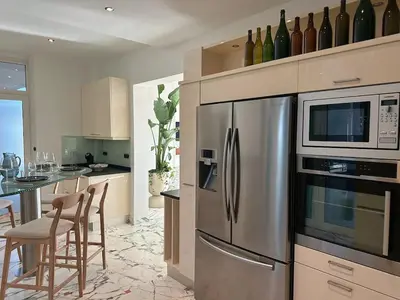 a kitchen with a stainless steel refrigerator and a table with chairs at Luxury Villa Pool & Sea View in Nice