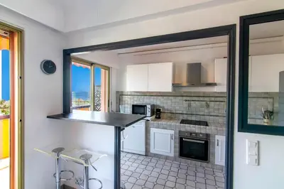 a kitchen with white cabinets and a counter top at 3 rooms panoramic sea view in Beaulieu-sur-Mer