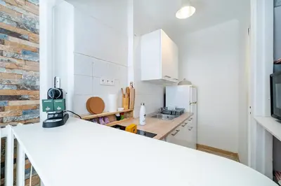 a kitchen with white cabinets and a brick wall at Studio proche mer avec jardin in Nice