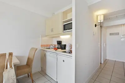 a small kitchen with white cabinets and a table at Résidence Héliotel Marine in Saint-Laurent-du-Var
