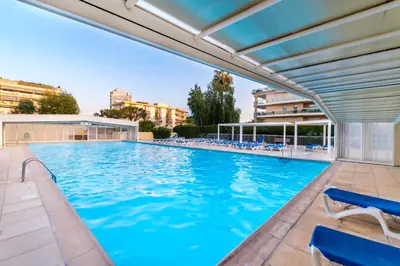 a swimming pool with blue water and chairs at Résidence Héliotel Marine in Saint-Laurent-du-Var