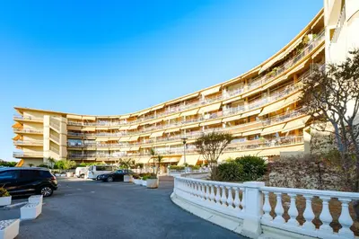 a large building with cars parked in a parking lot at Résidence Héliotel Marine in Saint-Laurent-du-Var