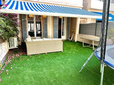 a porch with green grass and a blue and white awning at Wonderful apartment and garden heart of Nice in Nice
