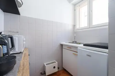 a white kitchen with a sink and a window at Studio Malaussena - Welkeys in Nice
