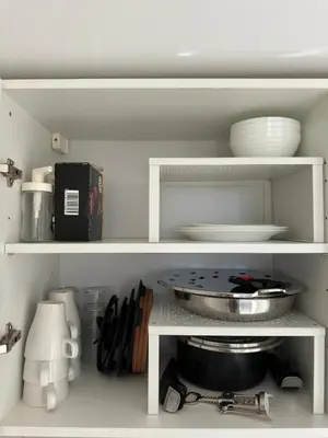 a kitchen shelf with plates and bowls and utensils at Panoramic Sea View Studio in Cagnes-sur-Mer