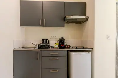 a kitchen with gray cabinets and a refrigerator at Nice Magnan studio avec jardin proche des plages in Nice
