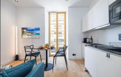 a kitchen and living room with a table and chairs at Cozy studio near the sea in Nice