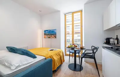 a bedroom with a bed and a table in a kitchen at Cozy studio near the sea in Nice