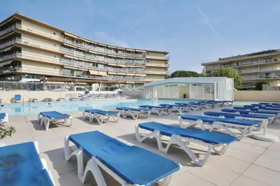 a pool with blue tables and chairs next to a building at Lovely 4-person studio - pool and sea in Cros-de-Cagnes