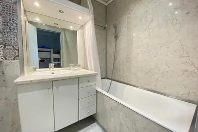 a bathroom with a sink and a tub and a mirror at Lovely 4-person studio - pool and sea in Cros-de-Cagnes