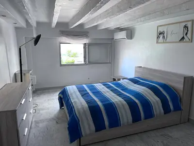 a bedroom with a blue and white bed and a window at duplex en bord de mer in Cagnes-sur-Mer