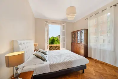 a bedroom with a white bed and a window at Villa Mi Rancho Vue mer - Jardin - Plage et resto à 5 min in Villefranche-sur-Mer