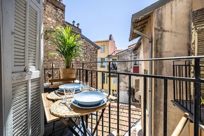 a balcony with a table with plates and glasses at Appartement neuf 2 pièces Port in Nice