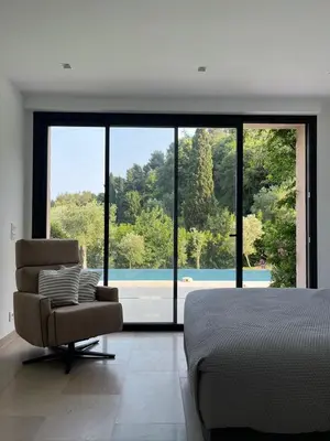 a bedroom with a bed and a chair and a large window at La perle - villa de luxe in Villefranche-sur-Mer