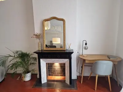a room with a fireplace with a mirror and a desk at Au Passage Niçois in Nice