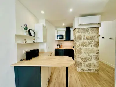 a kitchen with a table and a stone wall at AA G Cocon Lamartine - City center in Nice