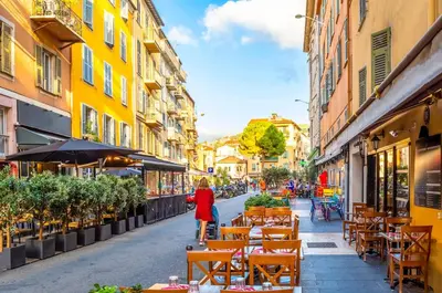 a woman walking down a street with tables and chairs at Cozy Apartment in Old Town Nice in Nice