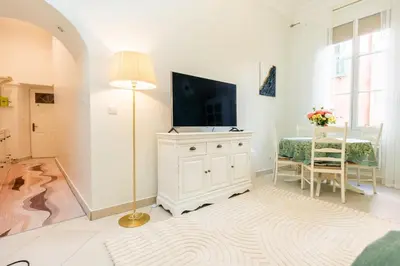 a white living room with a television and a table at Cozy Apartment in Old Town Nice in Nice