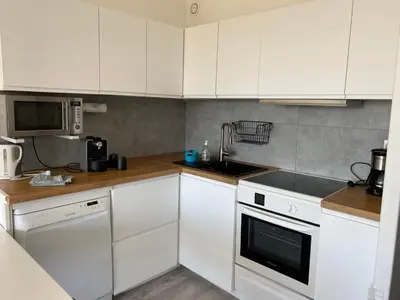 a kitchen with white cabinets and a sink and a microwave at Appartement Résidence Héliotel in Saint-Laurent-du-Var