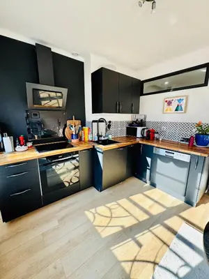 a kitchen with black cabinets and wooden floors at Nice experience in Nice