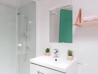 a white bathroom with a sink and a mirror at Apartment Le Mascoïnat by Interhome in Nice