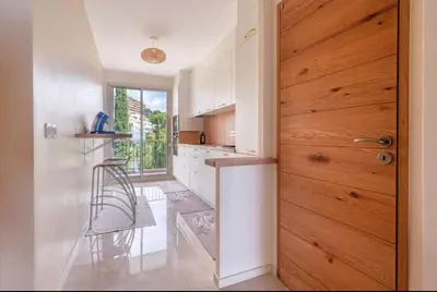 a kitchen with white cabinets and a wooden door at Le rêve bleu in Nice