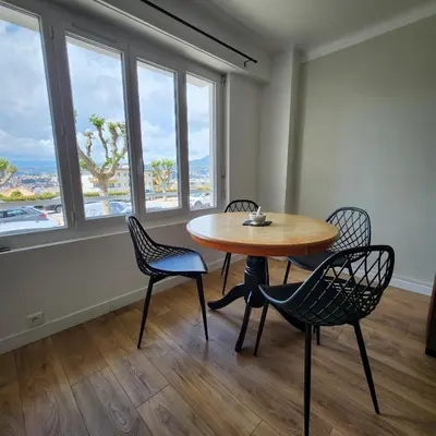 a table and chairs in a room with windows at Charmant appartement au calme à proximité du Port, de la vieille ville de Nice , de la Promenade des Anglais in Nice
