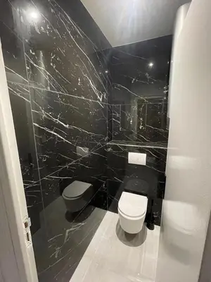 a black tiled bathroom with a toilet and a sink at Sea view apartment in Cagnes-sur-Mer