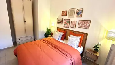 a bedroom with an orange bed and pictures on the wall at Chic & cosy proche mer in Nice