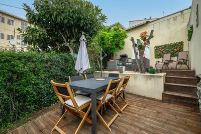 a table with chairs and an umbrella on a patio at Villa Nissarda, Maison Niçoise avec vue mer, parking, à 5 minutes du port in Nice