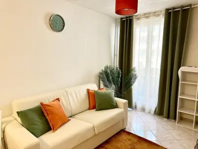 a living room with a couch and a clock on the wall at Studio Riviera - balcon et Wifi in Nice