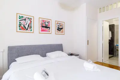 a bedroom with a white bed with three pictures on the wall at Palais D'orient in Nice