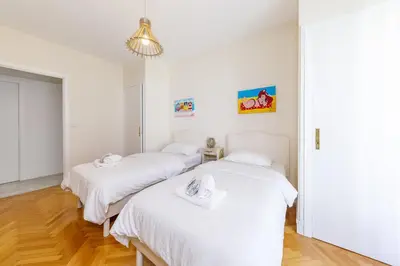 two beds in a room with white walls and wood floors at Palais D'orient in Nice