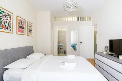 a white bedroom with a bed and a flat screen tv at Palais D'orient in Nice