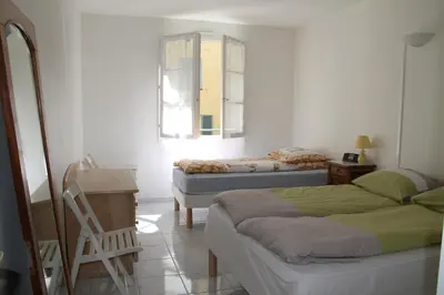 a room with two beds and a table and a mirror at Long stay in Old town of Nice, Castle Hill in Nice