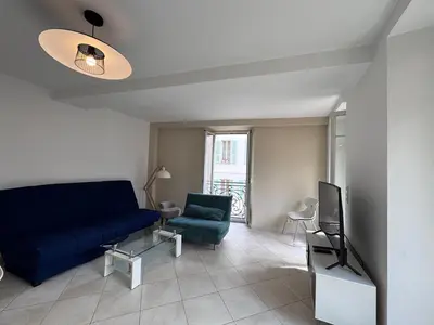 a living room with a blue couch and a tv at Beau 4 pièces - hyper centre 8 couchages in Nice