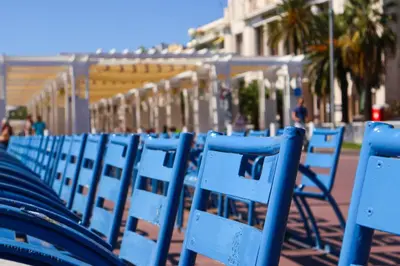 a row of blue chairs sitting on a street at Cap de Nice in Nice