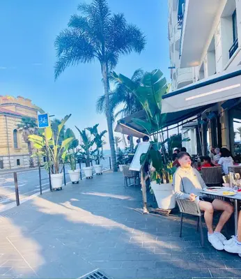 a woman sitting at a table next to the beach at A Studio at Nice Beach in Nice