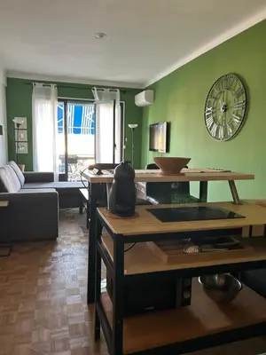 a living room with a table and a clock on the wall at A Studio at Nice Beach in Nice