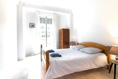 a bedroom with a bed with white sheets and a window at Résidence Estienne d'Orves in Nice