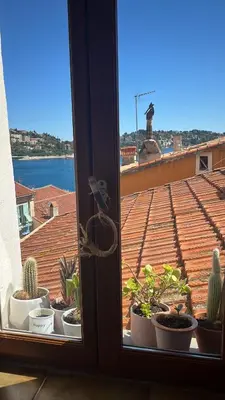 a window with a view of a roof with plants at Cosy Studio Sea view in Villefranche-sur-Mer
