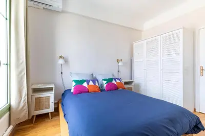 a bedroom with a blue bed with colorful pillows at Happyfew Cathedrale in Nice