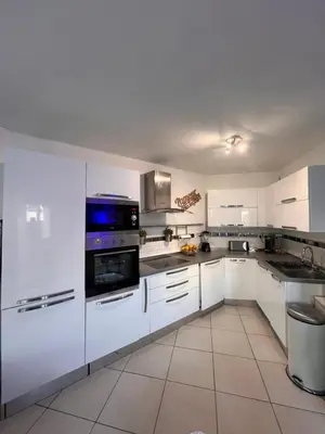 a white kitchen with white cabinets and appliances at Appartement rénové , Climatisé, Terrasse, Parking en sous sol in Saint-Laurent-du-Var