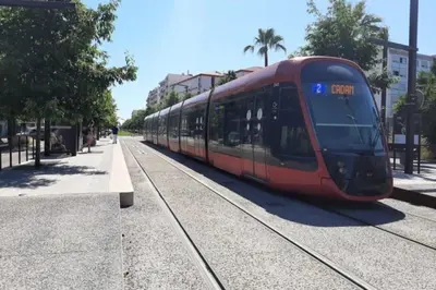 a red train on the tracks on a street at Studio Calif, face tram proche Mer in Nice