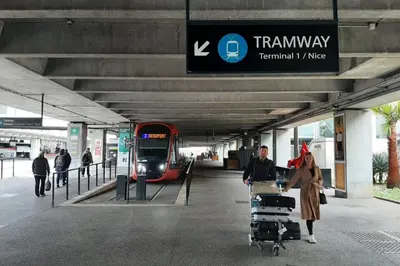 a woman pulling a cart in front of a train at Studio Calif, face tram proche Mer in Nice