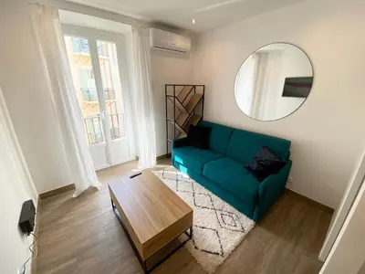 a living room with a green couch and a mirror at Studio calme et central avec clim in Nice