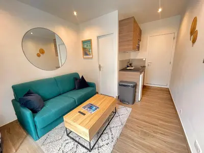 a living room with a green couch and a table at Studio calme et central avec clim in Nice
