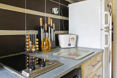 a kitchen with a counter top with a stove and a refrigerator at Studio climatisé au calme, terrasse vue colline in Nice